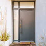 Grass in pot and wooden path in front of front door stylish suburban house